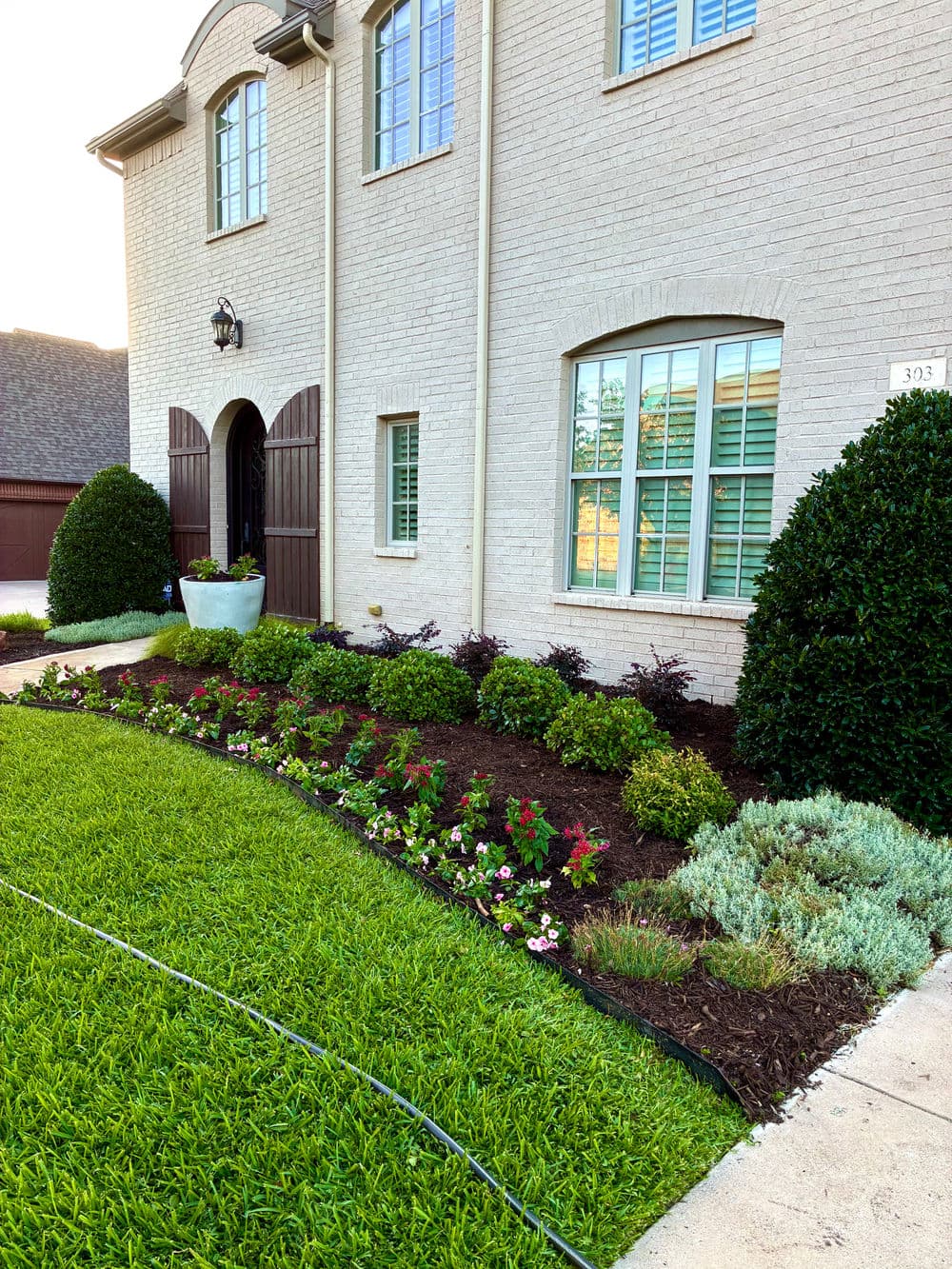 Beautifully landscaped front yard with colorful flowers, shrubs, and well-maintained grass.