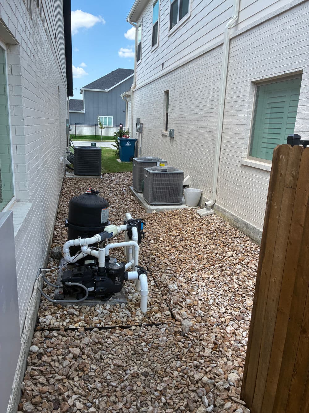 Side yard featuring air conditioning units and a water tank with gravel landscaping.