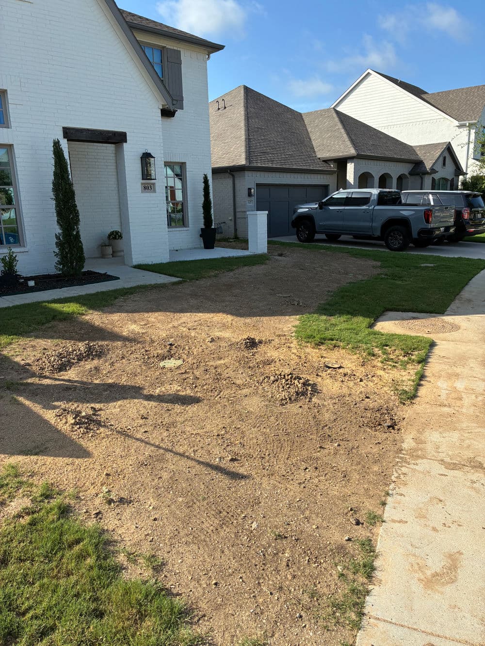 Home exterior with landscaping work in progress; grass and dirt patches visible.