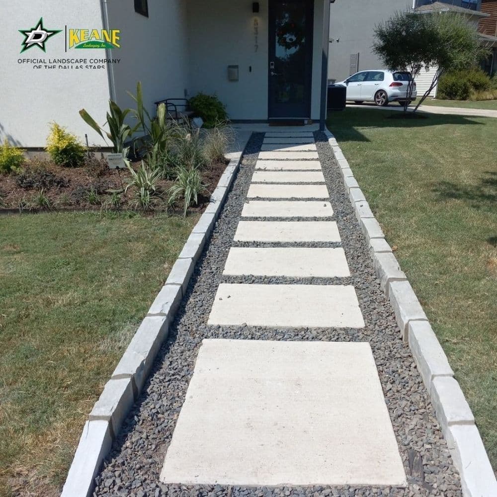 Modern stone pathway with gravel border leading to a contemporary house entrance.