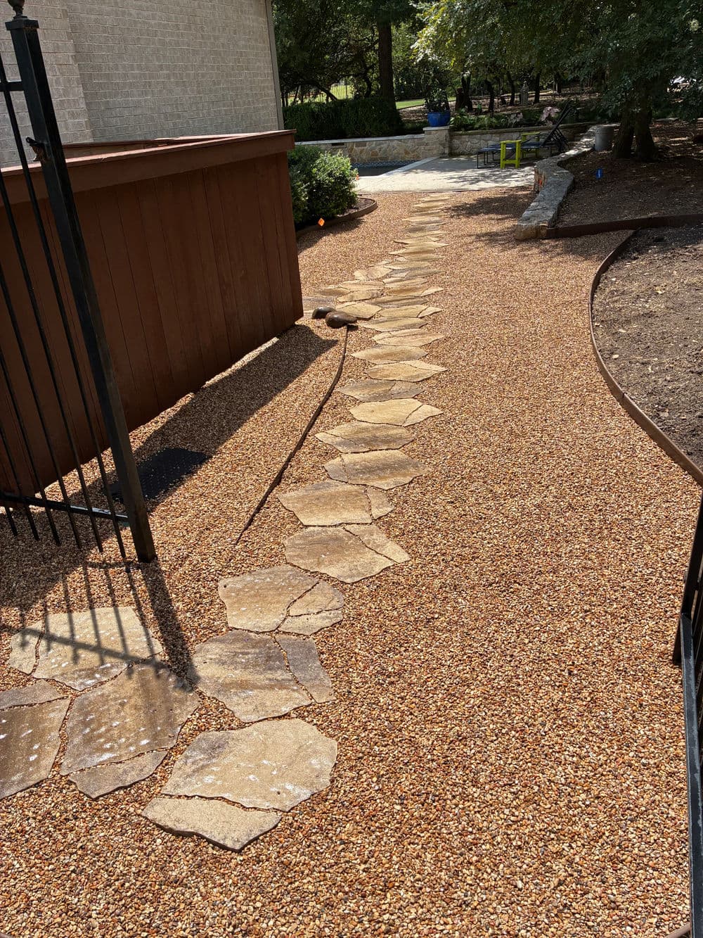 Stone pathway surrounded by gravel leading to a landscaped area in a garden setting.