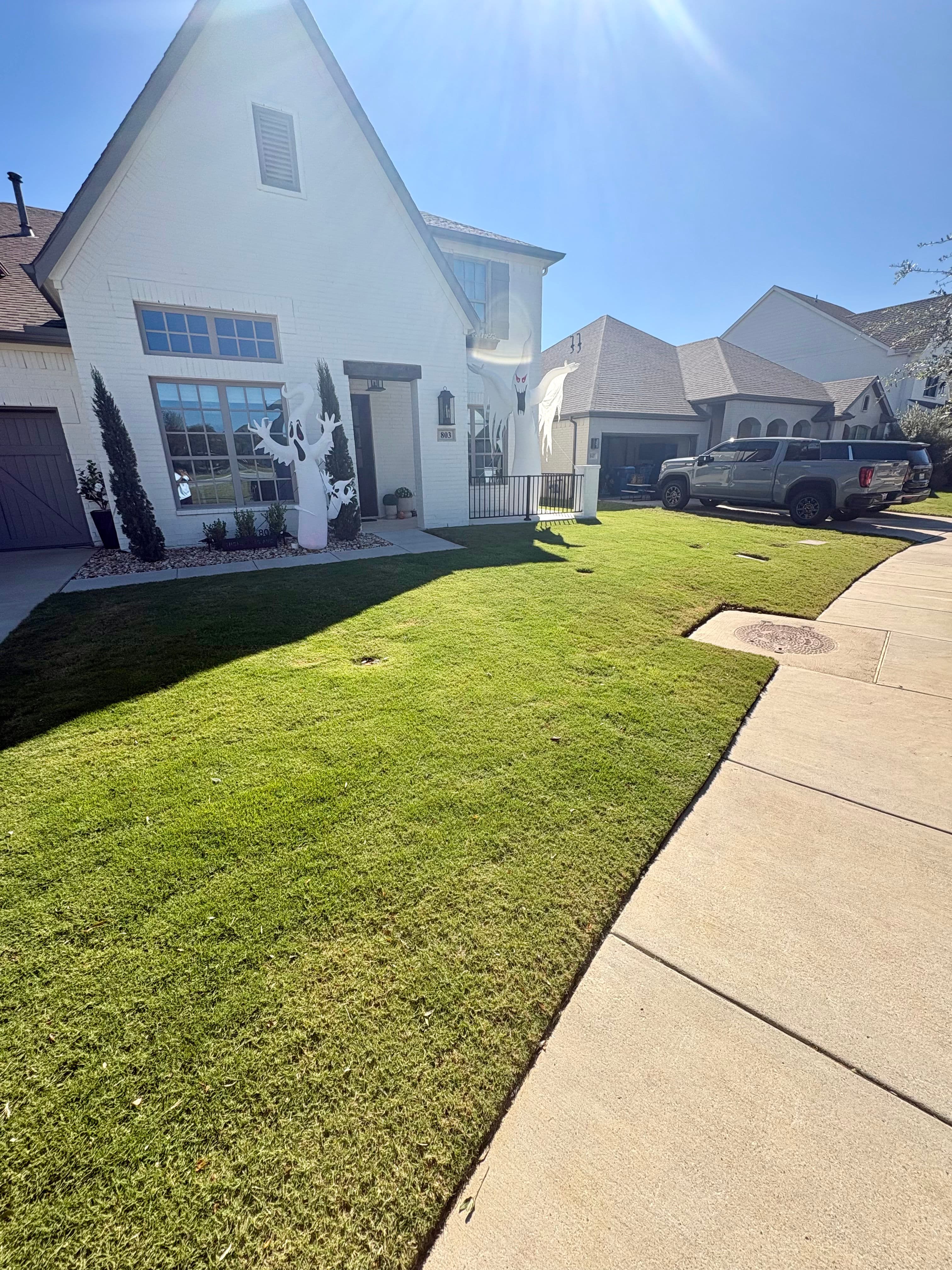 Modern white house with well-maintained lawn and a gray truck parked in the driveway.